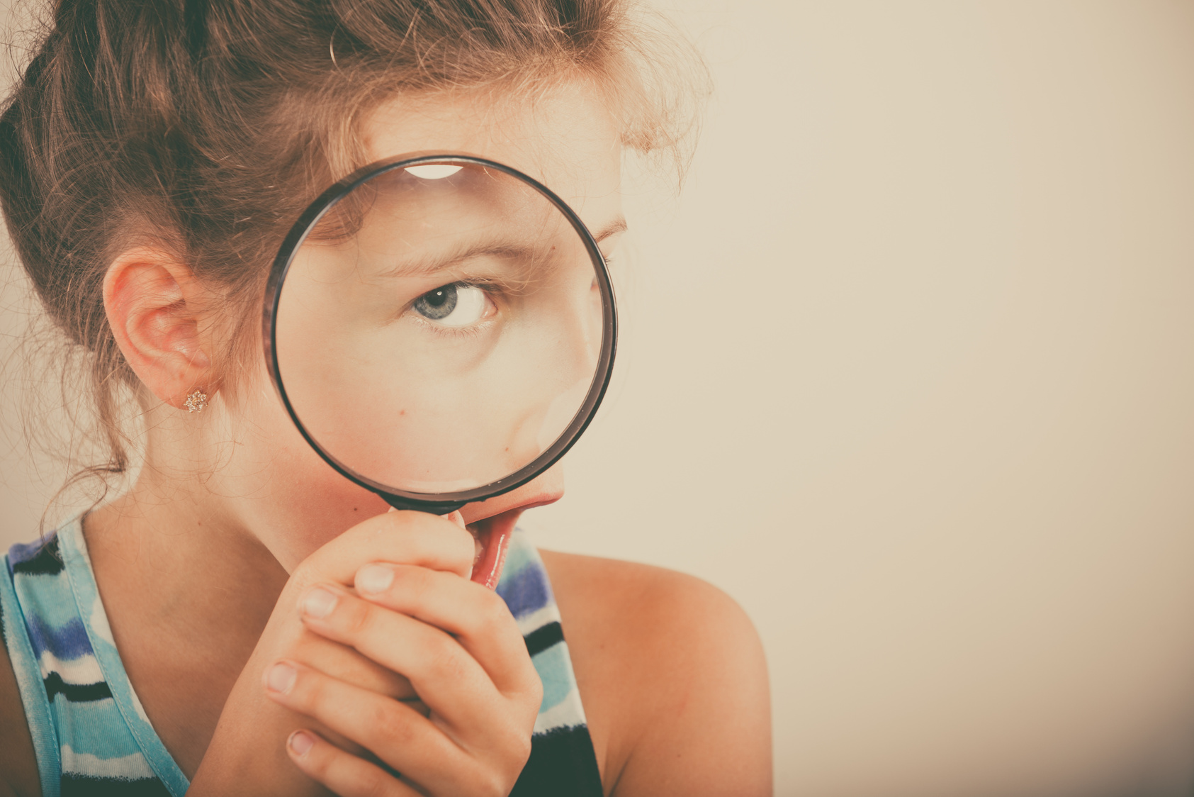 Little girl kid looking through magnifying glass.